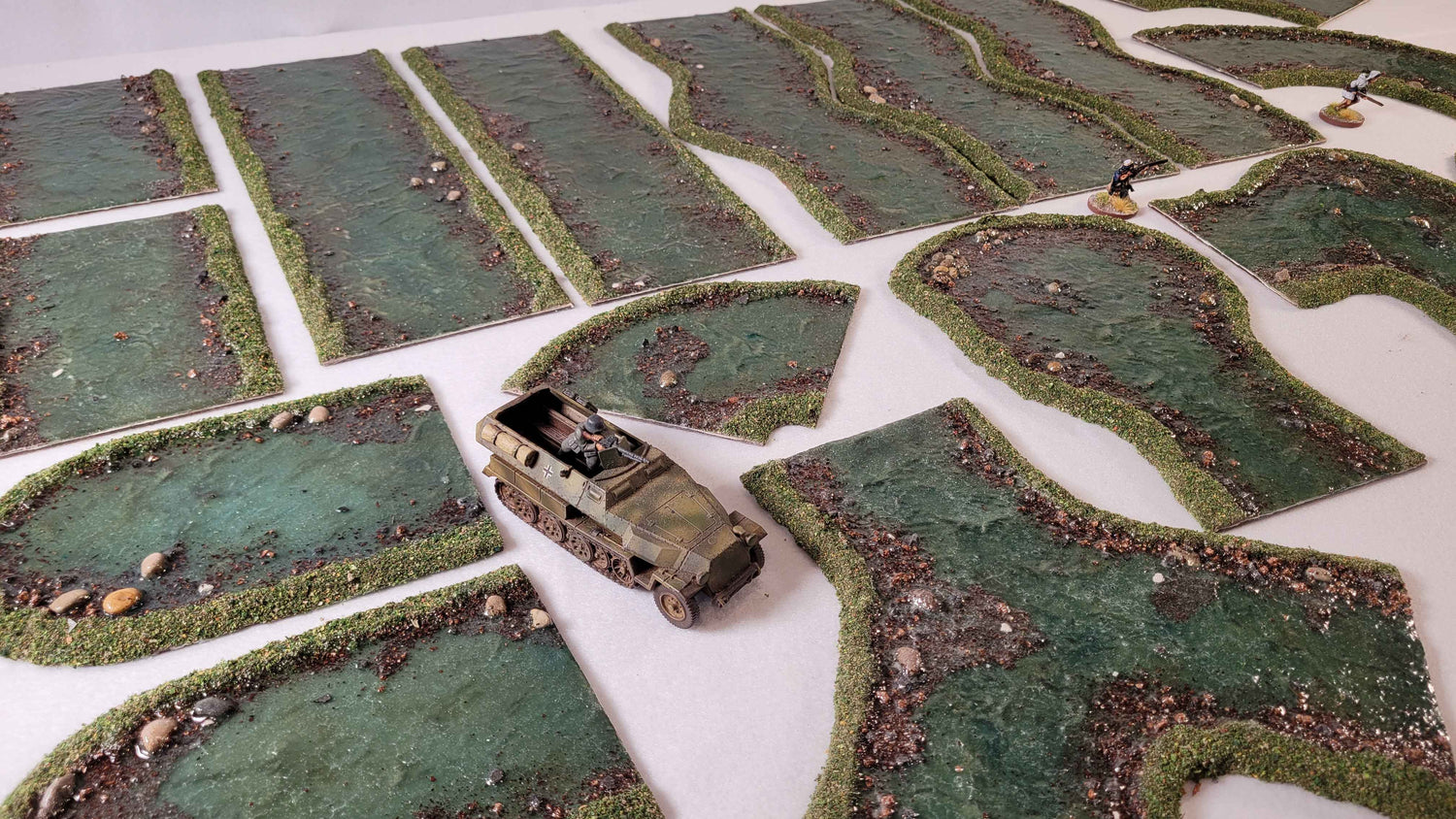 28mm scale WW2 halftrack and miniatures with handmade river terrain sections on gaming table