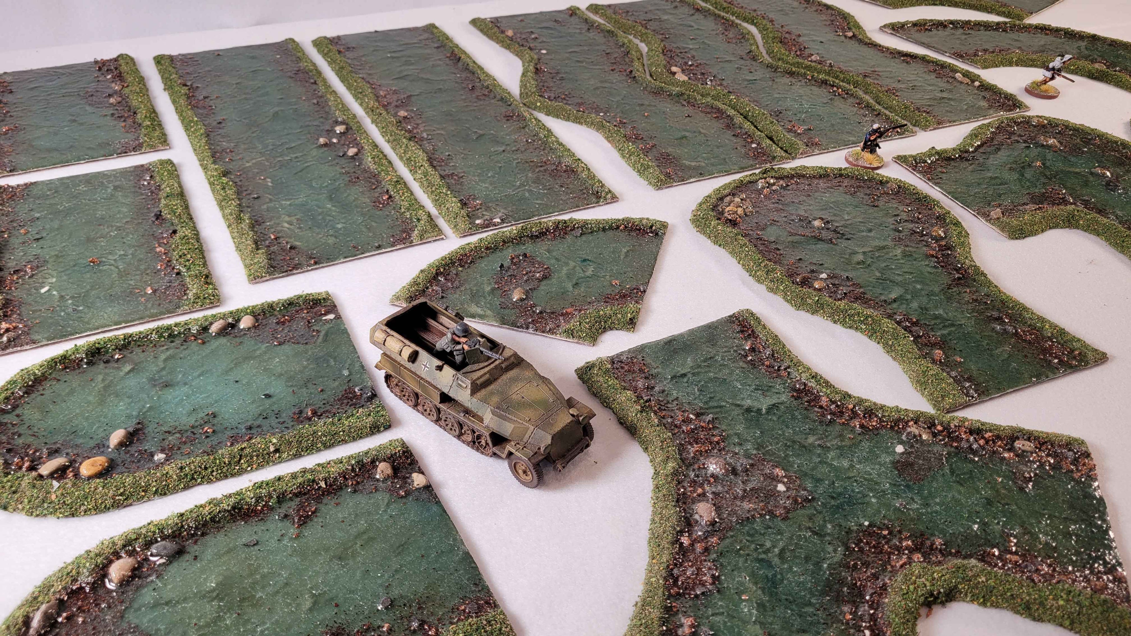 28mm scale WW2 halftrack and miniatures with handmade river terrain sections on gaming table