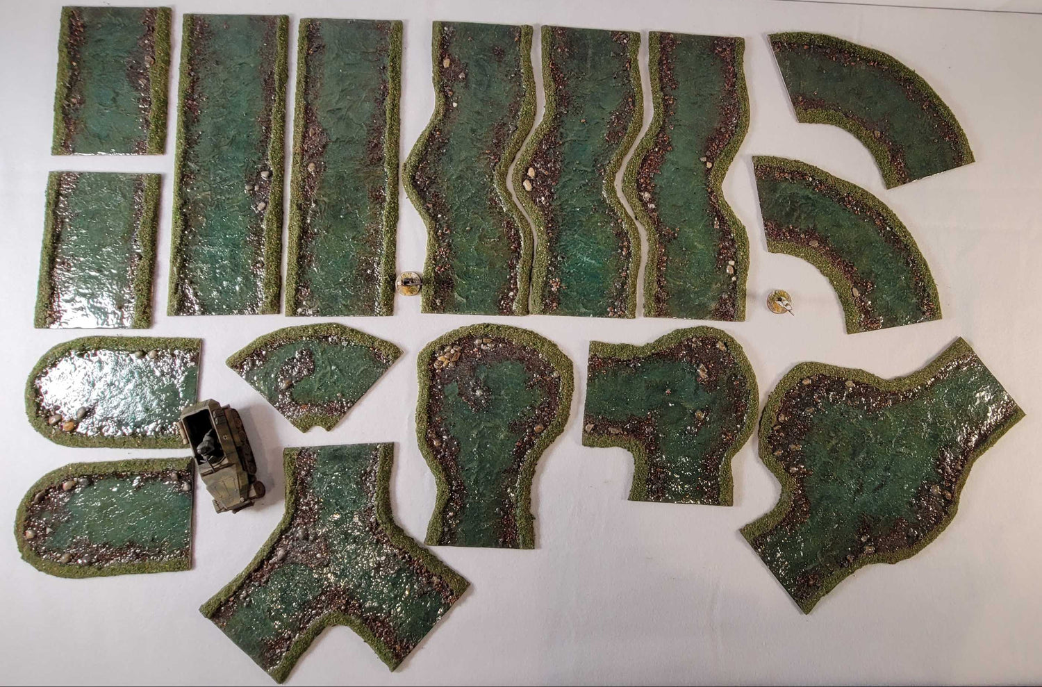 Handmade modular river terrain set for 28mm wargaming with curves, straights, and junction pieces
