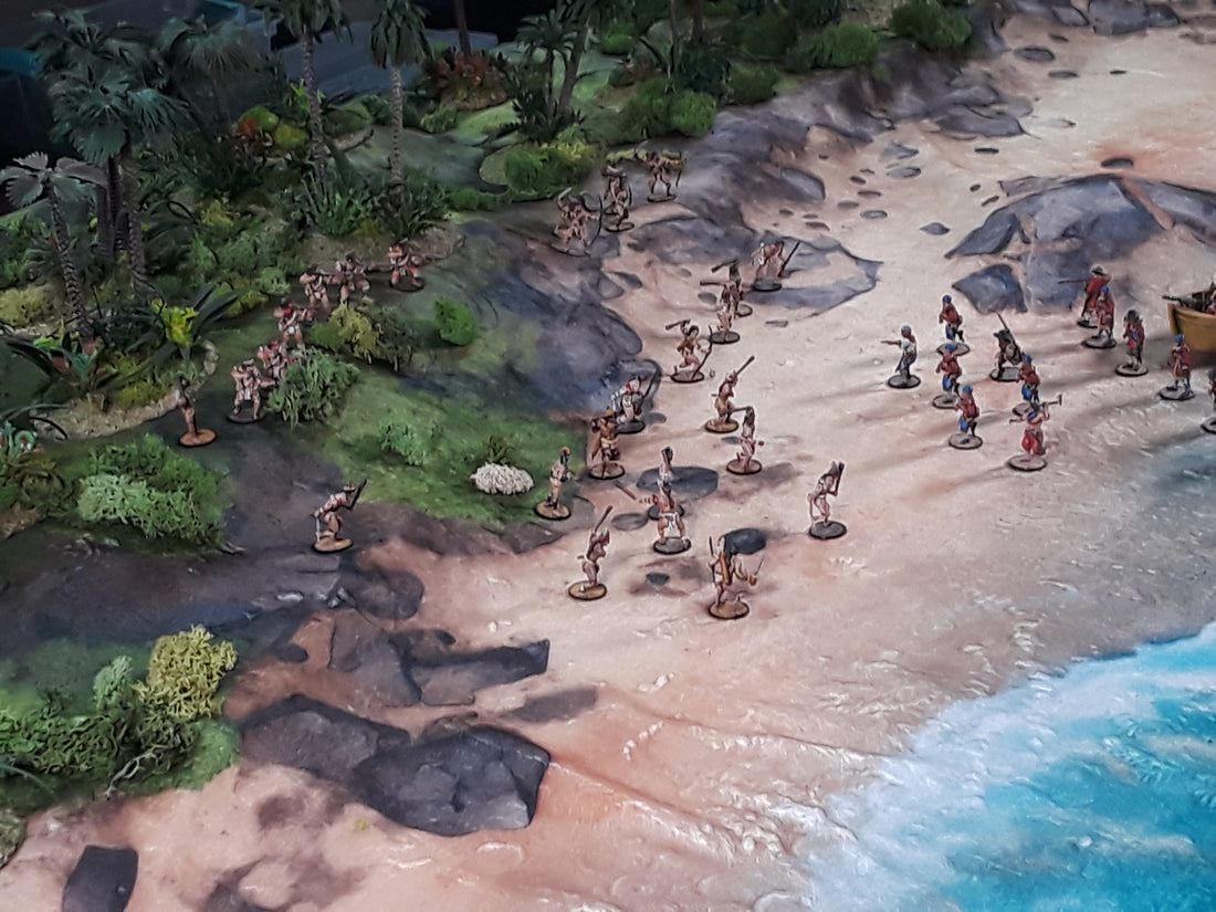 a group of toy figurines on a beach next to a body of water